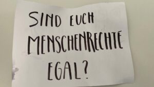 Ein Plakat auf das "Sind euch Menschenrechte egal?" geschrieben wurde